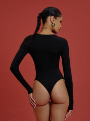 Model zeigt Rückansicht des Saint Sass Kaia Jersey Body in Schwarz, figurbetonte Passform mit langen Ärmeln, vor rotem Hintergrund.