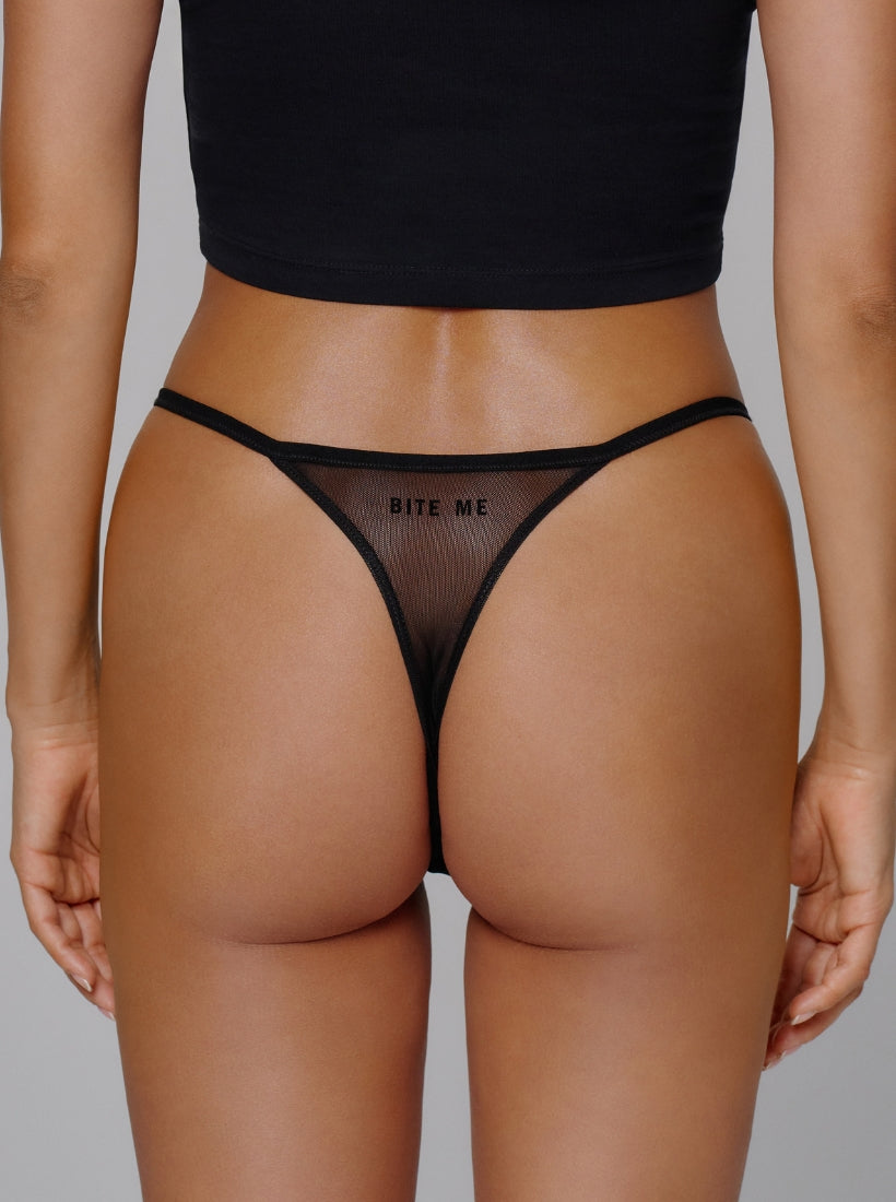 Schwarzer Mesh Tanga mit Bite me Flockdruck auf der Rückseite. Von saint sass.