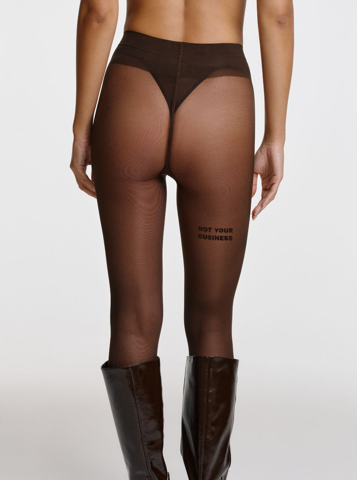 Chocolate Brown NOT YOUR BUSINESS Statement Strumpfhose von saint sass mit braunem NOT YOUR BUSINESS Schriftzug auf der Rückseite des Oberschenkels. In transparenter, weicher Qualität und figurbetonter Passform.