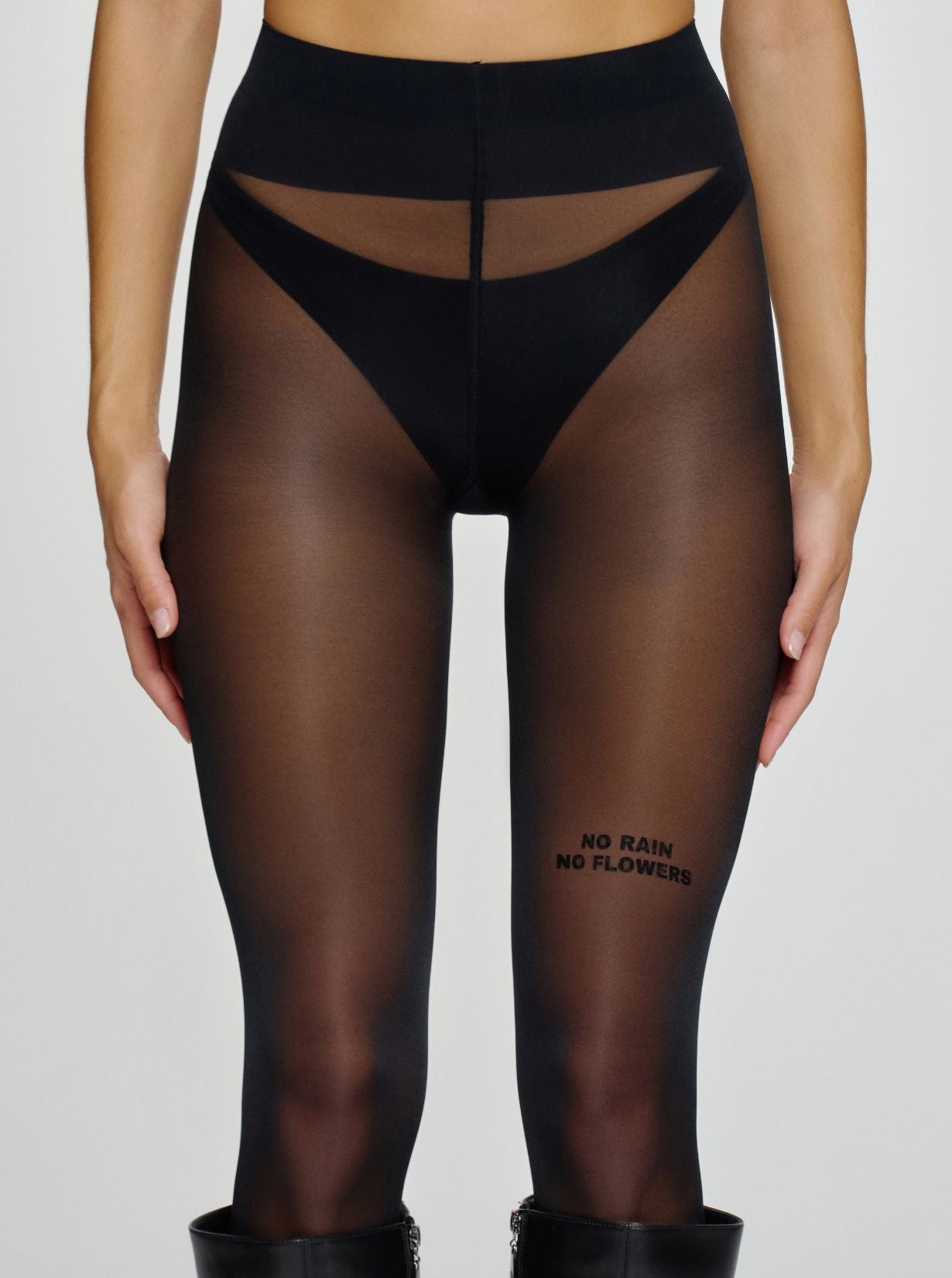 Model trägt schwarze Statement-Strumpfhose mit „NO RAIN NO FLOWERS“-Schriftzug am Oberschenkel.