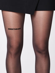 Die Statement Strumpfhose von saint sass mit dem Statement Sweetheart vorderen Oberschenkel. In 40 den und semi-transparenter Optik.